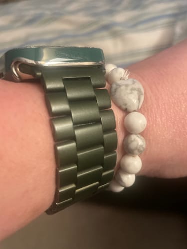 Customer's wrist showing the Howlite crystal bracelet with marbled beads and a heart charm, styled next to a watch.