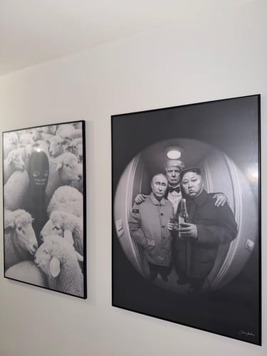 Reviewer's 'The Neighbors' art print, framed in black and hanging on a wall next to another piece.
