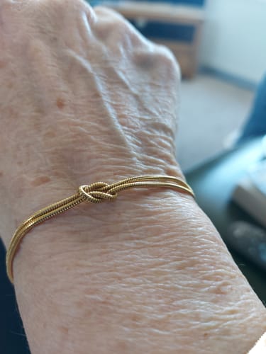 Customer showing a delicate gold-colored knot bracelet on their wrist.