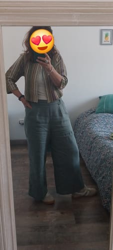 Cliente portant le chic boléro Ange à motif jacquard, associé à un pantalon large vert.