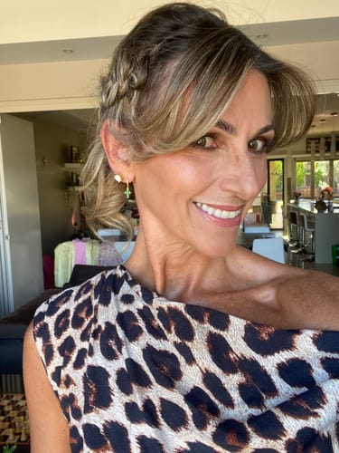 Reviewer smiling, wearing the gold Emerald Cross Zirconia Huggie Earring in a side-profile view.