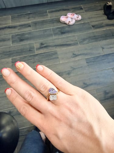 Customer wearing the Navae Birthstone Ring on their hand, showing the purple and clear stones. The ring appears slightly large.