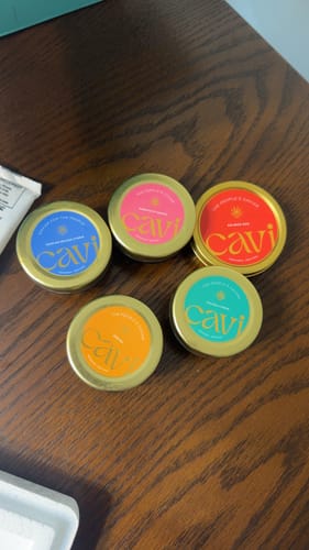 Customer's five colorful Cavi caviar tins received in good condition on a wooden table.
