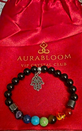 Customer's beaded crystal bracelet with a silver charm, shown in front of its red VIP Crystal Club pouch.