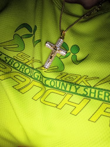 Customer's sparkling Jesus Crucifix Paved Necklace shown on a bright green shirt.
