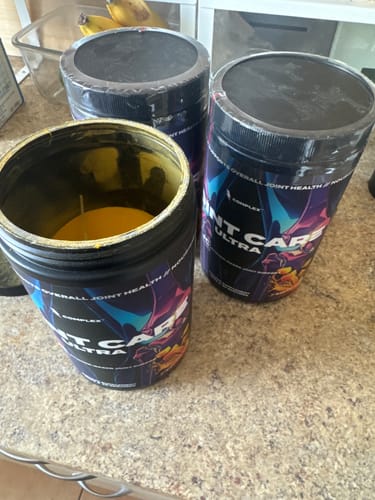 Customer's three containers of Joint Care Ultra on a counter, one of which is open showing the yellow powder.