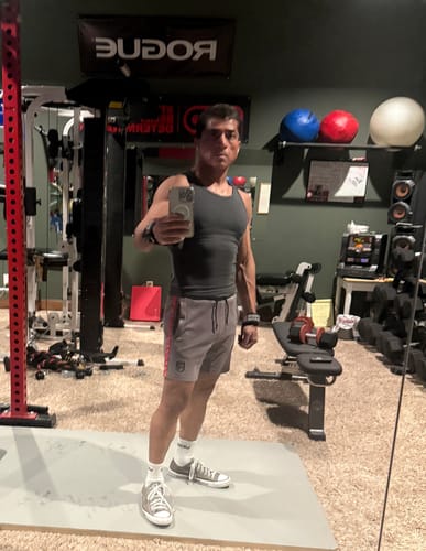 Reviewer in a home gym wearing the fitted, dark grey Cotton Tank.