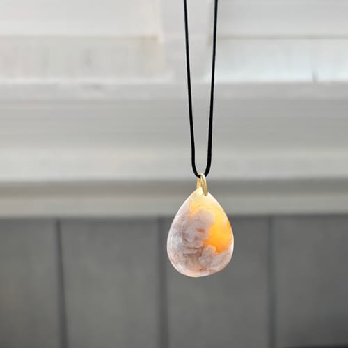 Photo d'un client du Collier Agate Fleur, un pendentif en forme de goutte sur son cordon noir.