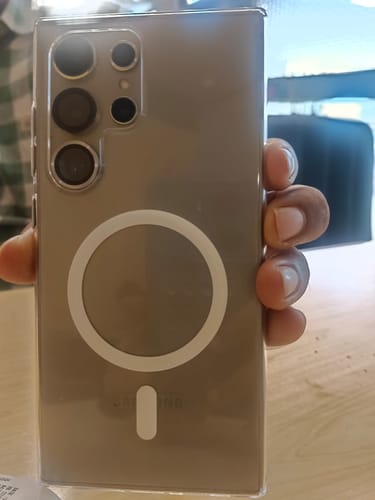Customer holding a smartphone in a clear case with a white ring on the back.