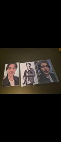 Customer's three BTS "ARIRANG" Withmuu Lucky Draw Event Photocards from the set, laid out on a dark surface.