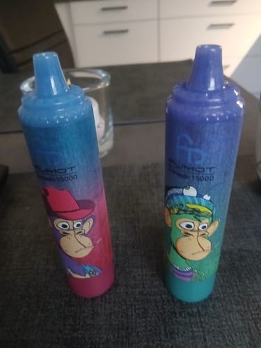 Rezensent zeigt zwei verschiedenfarbige RANDM TORNADO 15000 Vapes, die auf einem Tisch stehen.