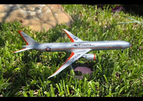 Customer's Gemini200 American 777-300ER model plane in silver with orange accents, displayed outdoors on a green lawn.