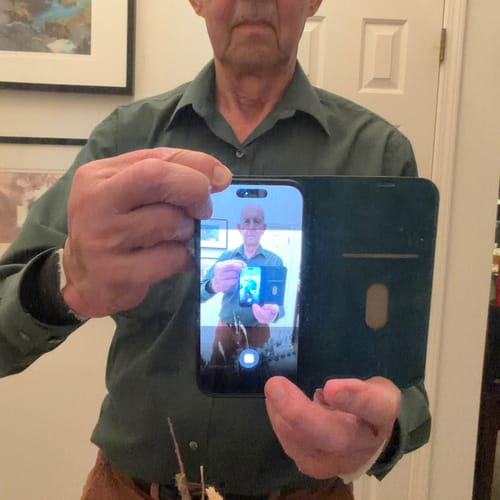 Reviewer holds the green MagCase Wallet open, showing the phone inside and the interior wallet flap.