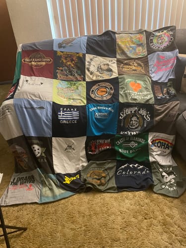 Customer's custom Project Repat T-Shirt Quilt made of many colorful shirts, fully spread out over a sofa.