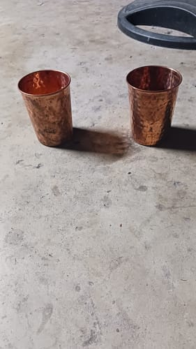 Customer's two hammered copper glasses from the Artisan set on a concrete floor.