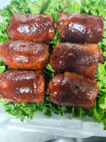 Customer's six chicken thighs glazed with a thick, dark Competition BBQ Sauce, arranged on lettuce.