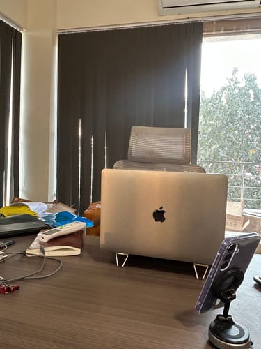 Reviewer's silver laptop propped up on a desk by the small Casence AirStand.