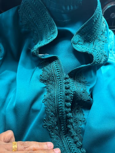 Close-up of the customer's teal Caftan Dounia, showing the soft material and intricate embroidery on the collar.