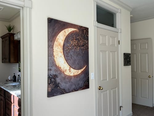 Customer's crescent moon canvas decor hanging on a light-colored wall in a hallway, viewed from an angle.