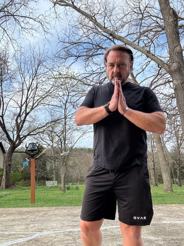 Customer wearing the black performance shorts outdoors with his hands in a prayer pose.
