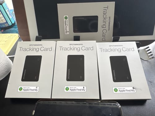 Customer's four black SPOTMINDERS Tracking Cards displayed in their white packaging on a desk.