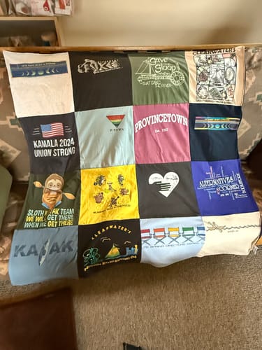 Customer's colorful Project Repat T-Shirt Quilt made from various shirts, draped over a couch.