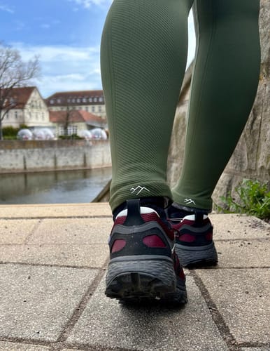 Nahaufnahme eines Kunden, der die grünen Tofana-Leggings bei einem Spaziergang im Freien trägt.
