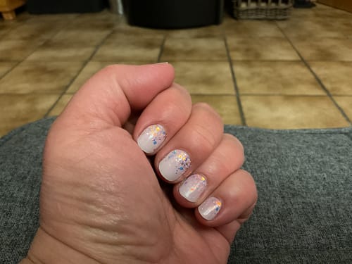 Eine Kundin zeigt ihre kurzen Nägel mit den glitzernden UV-Gelfolien „Babyboomer Princess“.