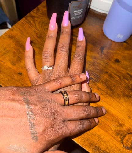 Customer wearing the Titanfall ring, showing the black band with gold inlay, with their hand held by another.