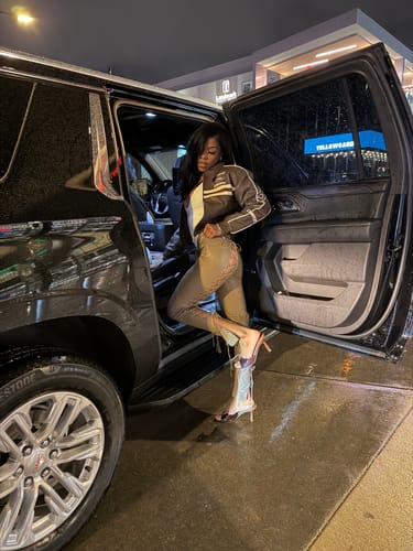 Reviewer posing by a car at night in the low-rise tan Vice Pant, showing the side lace detail.