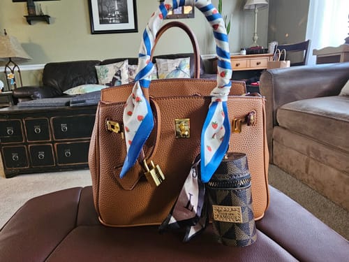 Customer's brown, pebbled LALUVA Warkin Bag styled with a decorative scarf on the handle, resting on an ottoman.