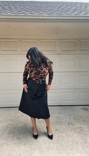 Reviewer wearing the fitted Naked Print Mock Neck Top, tucked into a black skirt.