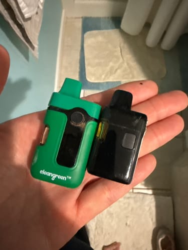 Customer holds two Create Vapes in their hand, comparing a larger green one to a smaller black one.