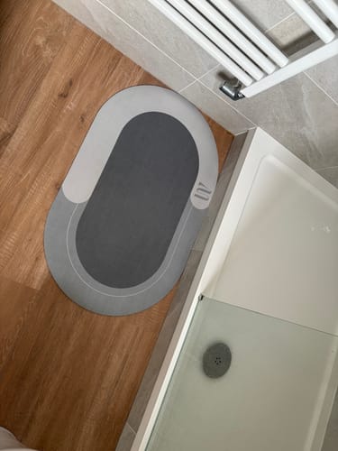 Customer's two-tone gray Magic Mat on a wood-look bathroom floor next to a shower.