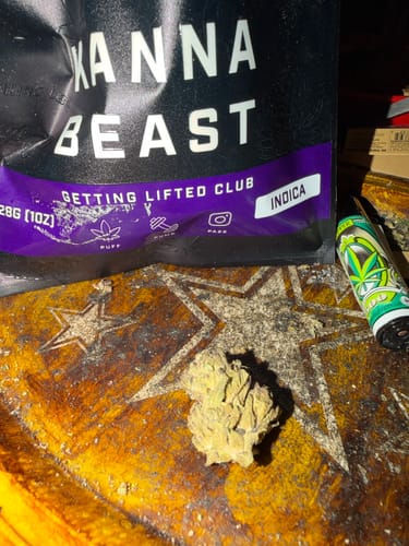 Reviewer's light-green bud of Banana Pie flower on a wooden surface, with the Kanna Beast packaging visible.