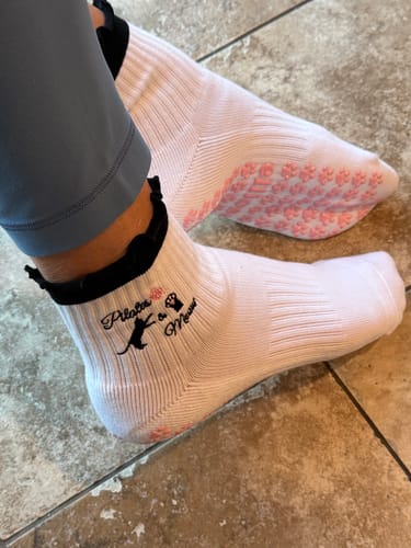 Customer wearing Pilates & Meow socks showing the black ruffled cuff and pink paw-print grips on the sole.