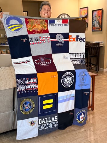 Customer proudly holding up their large, colorful Project Repat T-Shirt Quilt made from a variety of memorable t-shirts.