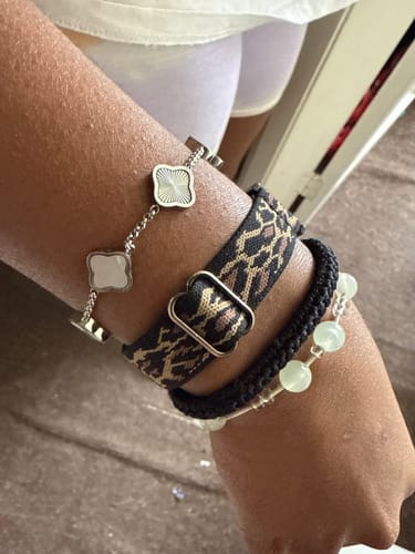 Customer's wrist showing the Celine Silver Clover Bracelet layered with other bracelets.