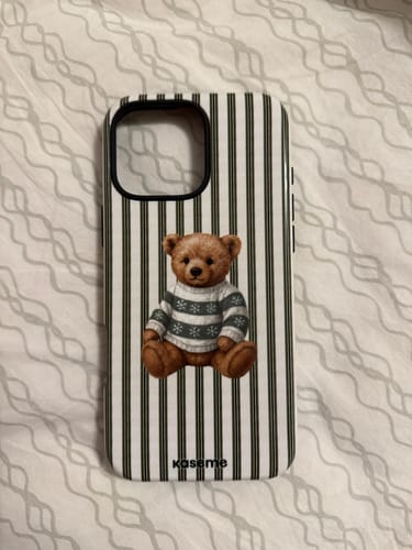 Customer's Theodore phone case with a cute teddy bear design and striped background, laid on a patterned surface.