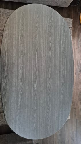 Anmelderens ovale bord dekket med mørk Manchester blackwood kontaktplast, sett ovenfra.