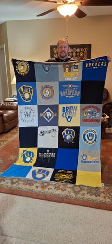 Reviewer holding up their large Project Repat T-Shirt Quilt made from colorful baseball-themed shirts.