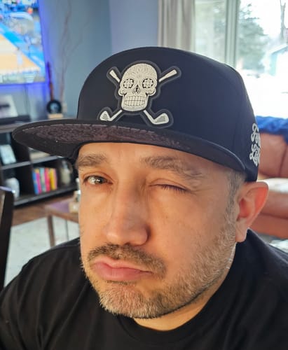 Reviewer wearing the black Sugar Skull Golf Hat while winking and making a playful, tough face.