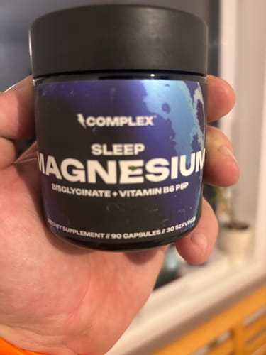 Customer holds a black jar of Complex Sleep Magnesium supplement in their hand.