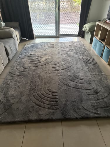 Customer's charcoal Mellow Mat with its carved 3D design laid out in a living room on a tiled floor.