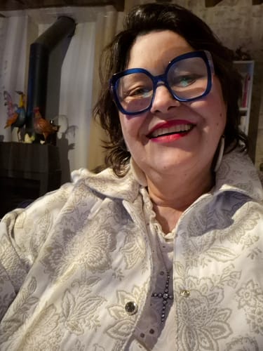 Cliente souriante portant la Veste Solveig Jacquard à motif floral.