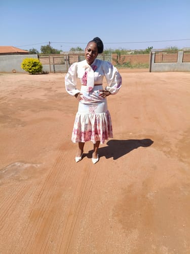 Customer gives a full view of the white Floral Print Bottom Pleated Dress while posing outdoors.