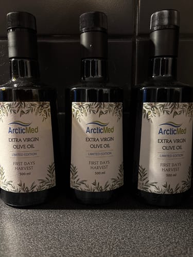Kundens tre flaskor ArcticMed Extra Virgin Olivolja uppradade på en mörk bänk.