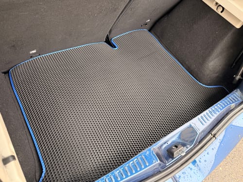 Recenzenta czarna mata do bagażnika z niebieskim obszyciem, idealnie dopasowana do bagażnika auta.