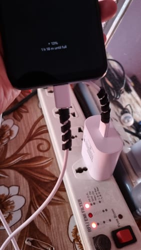 Reviewer showing the two black cable protectors installed on a phone charger.