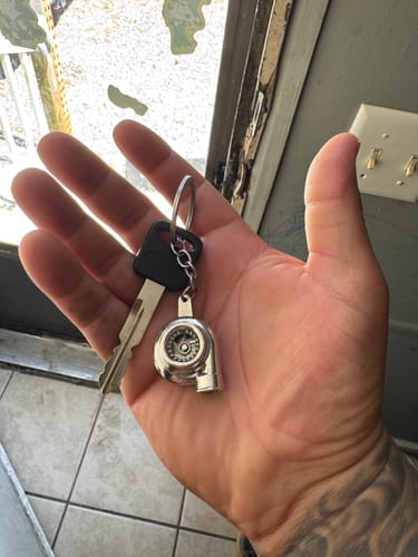 Reviewer holding the metal Turbo Keychain and a key in their hand.